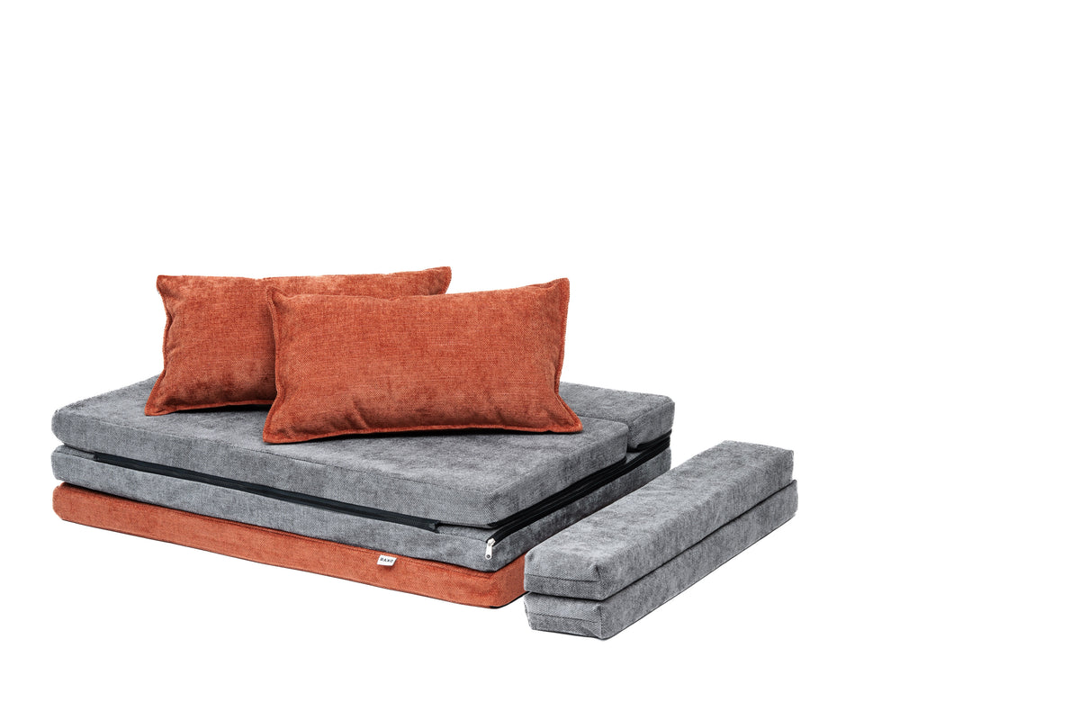 Oransje og grå puter lagt som sofa